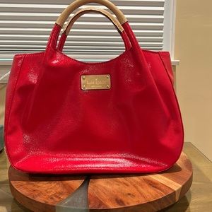 Kate Spade red shiny handbag. Light leather handles and matching leather tags.